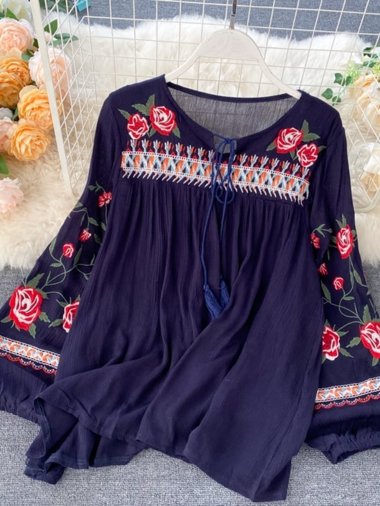 Blouse bleue avec des fleurs rouges accrochée à un cintre