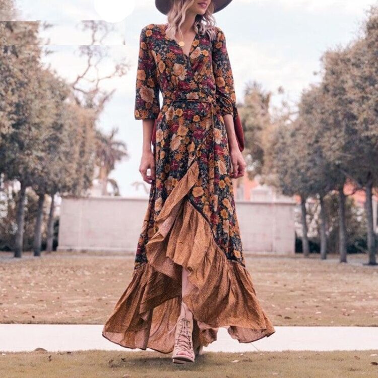 Mannequin femme qui porte une robe longue bohème à fleurs avec un chapeau et des bottes elle se situe dans un parcs avec plein d'arbres à gauche et à droite