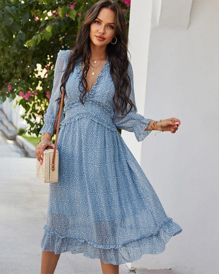 Femme portant une robe fleurie bleue ample et fluide avec un sac en osier sur son épaule droite